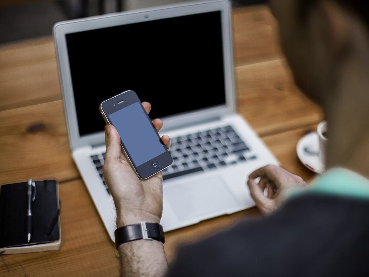 Checking a phone beside a laptop